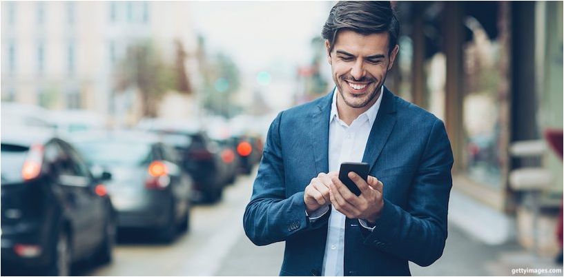 młody biznesmen patrzy na telefon i uśmiecha się