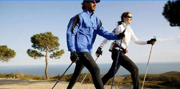 Mężczyzna i kobieta uprawiają nordic walking.